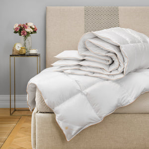 beautiful white down comforter folded on bed